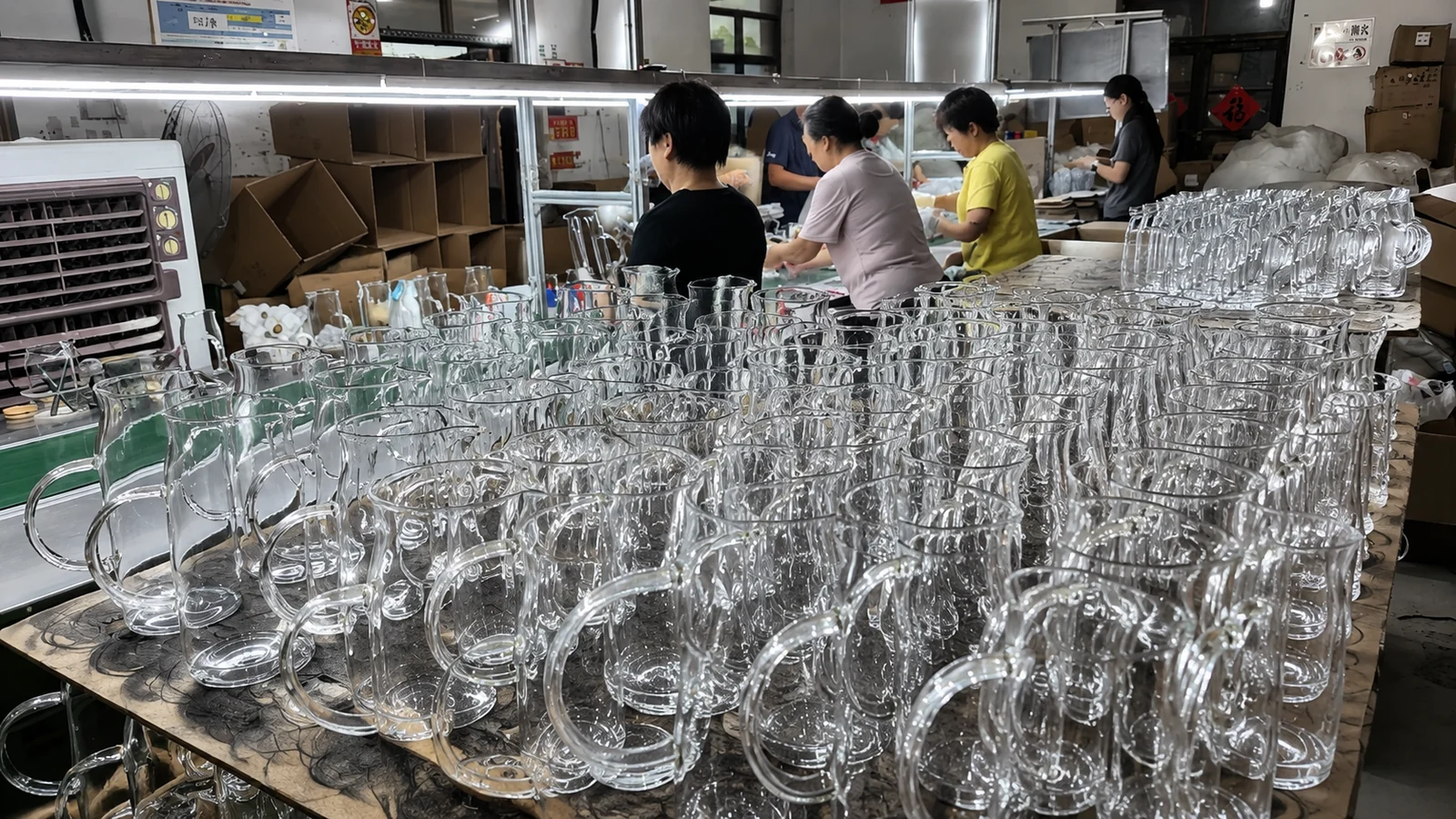 Clear glass pitchers at a manual handling and quality checking station